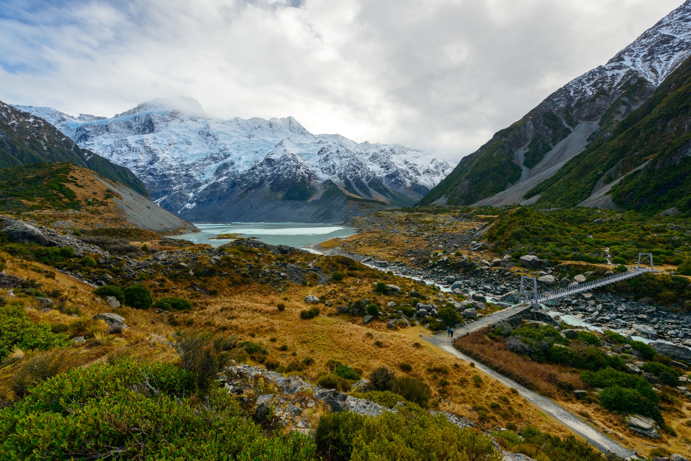 Mueller Lake beneath snowy mountains, with the first swing bridge in the foreground